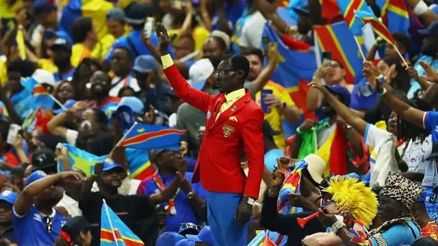 Lumumba Vea parado con el brazo en alto durante el partido entre la República Democrática del Congo y Colombia
