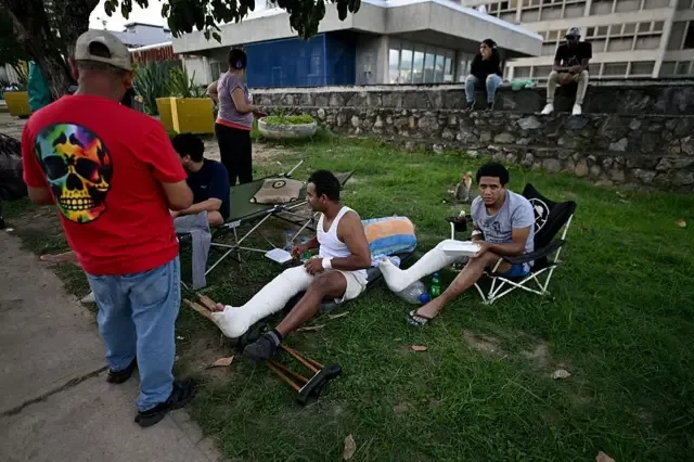 Personas heridas con escayolas en las piernas permanecen en el exterior del hospital Domingo Luciani de Caracas el 25 de junio de 2026, tras los dos terremotos que sacudieron la capital venezolana.