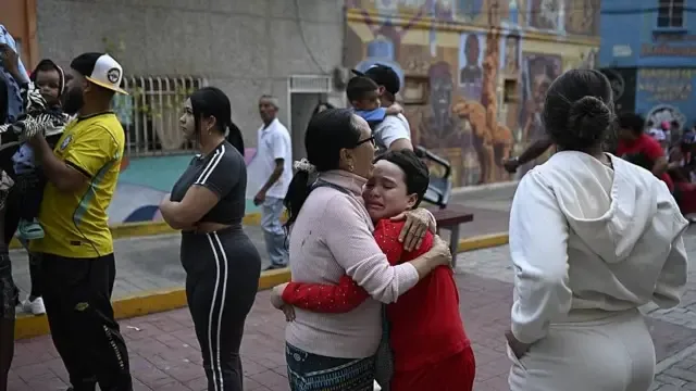 Una mujer consuela a un niño en la calle en Caracas. Tambén se ve a otras personas que permanecen en la calle por temor a réplicas