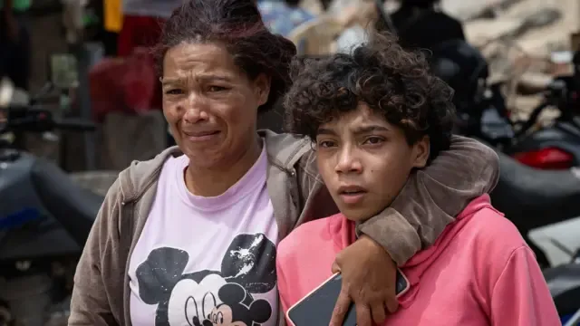 Dos personas compungidas, rodeadas de la destrucción causada por los terremotos de Venezuela.