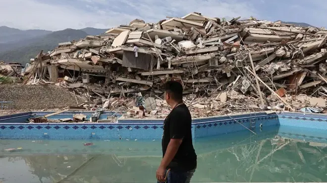 Residente de La Guaira camina ante un edificio completamente destruido